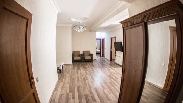 A spacious hallway with wooden flooring, a chandelier, and two sofas in the background. - Bakuvi Tourist Apartment B098 (Baku)