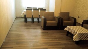 A living room with a wooden floor, a dining table with chairs, and two sofas. - Bakuvi Tourist Apartment B098 (Baku)