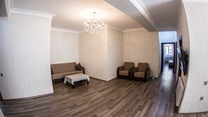 A spacious living room with a high ceiling, a chandelier, a sofa, two armchairs, and a coffee table. - Bakuvi Tourist Apartment B098 (Baku)