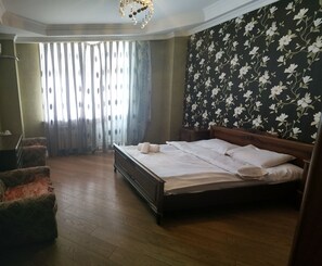 A bedroom with a wooden bed, floral wallpaper, and a wooden floor. - Apartment 3 rooms 6 Bakuvi (Baku)