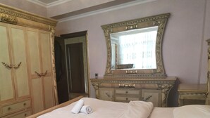 A bedroom with a large bed, wooden wardrobe, and a mirror above the dresser. - Apartment 3 rooms 6 Bakuvi (Baku)
