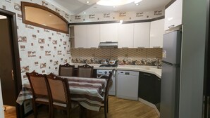 Une cuisine compacte avec un coin repas, comprenant une table avec des chaises, un réfrigérateur, un lave-vaisselle et un lave-linge.