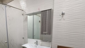Une salle de bain avec un lavabo blanc, un miroir et une douche.