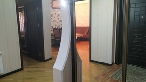 Un couloir avec un plancher en bois, un mur recouvert de miroirs et un canapé au fond.