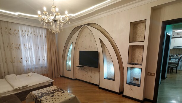 Un salon spacieux avec un grand canapé, une table basse et un téléviseur fixé sur un mur incurvé.