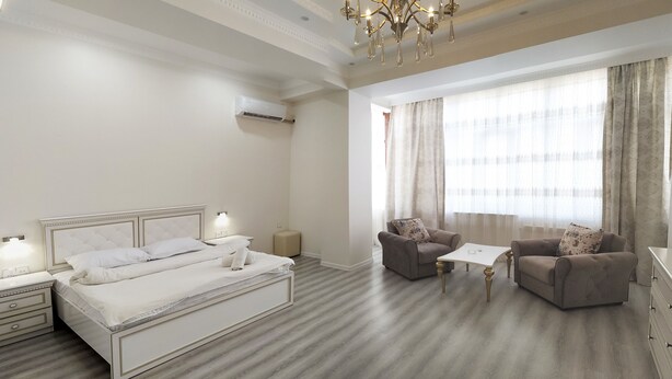 A hotel room with a bed, two armchairs, a small table, and a chandelier. - Bakuvi Tourist Apartment B097 (Baku)