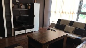 A modern living room with a flat-screen TV, a wooden coffee table, a sofa, and a cabinet.