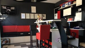 A modern office space with a black and white checkered floor, red and black chairs, a white desk, and shelves with various items.