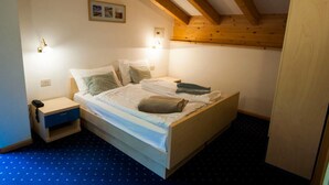 A bedroom with a bed, bedside tables, and a wooden ceiling. - Garni Col da la Vila (Canazei)