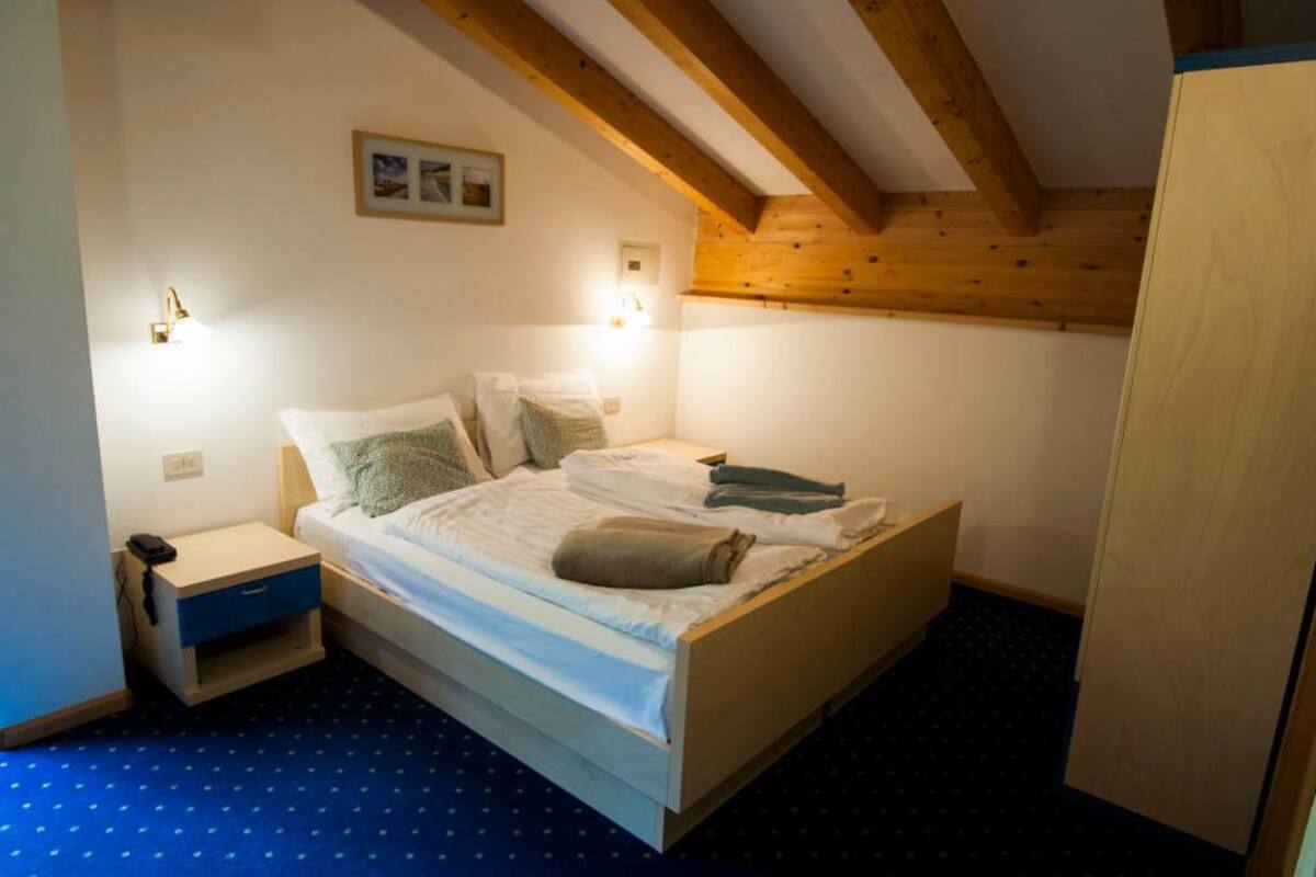 A bedroom with a bed, bedside tables, and a wooden ceiling.