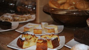 A variety of desserts on plates, including cakes and pastries, on a wooden table. - Garni Col da la Vila (Canazei)