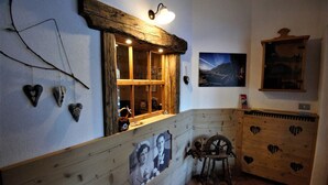 A rustic room with wooden walls, a wooden bench, a vintage sewing machine, and a framed photograph. - Garni Col da la Vila (Canazei)