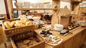A buffet counter with various breads, pastries, and desserts. - Garni Col da la Vila (Canazei)