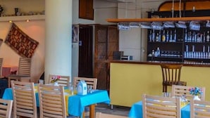 A restaurant with wooden chairs and tables, a bar area with bottles, and a patterned wall hanging. - Seckin Motel (Ayvacik)