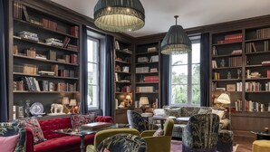 Una biblioteca con estanterías, un sofá rojo y varias sillas.