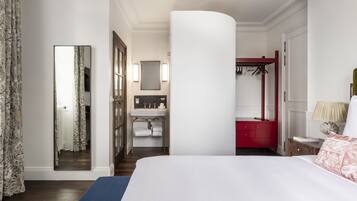 A hotel room with a large bed, a bathroom with a sink and mirror, and a red wardrobe.