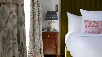 A bedroom with a green headboard, a wooden nightstand with a lamp, and a patterned rug on the floor.