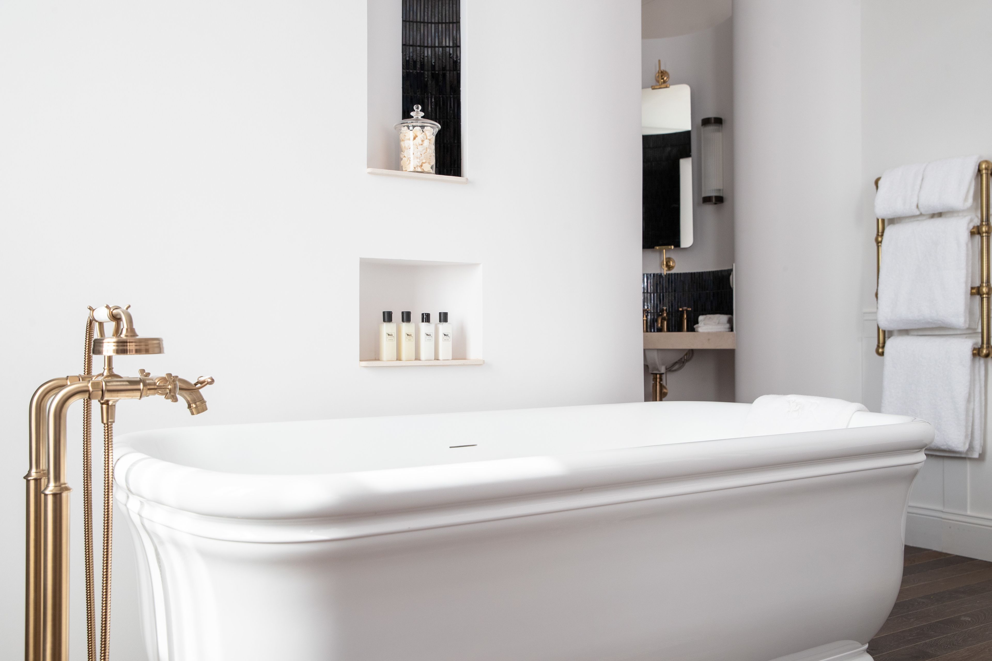 A modern bathroom with a freestanding bathtub, gold fixtures, and minimalist decor.