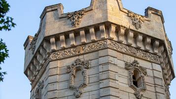 Uma torre de pedra com esculturas elaboradas e duas janelas em arco.