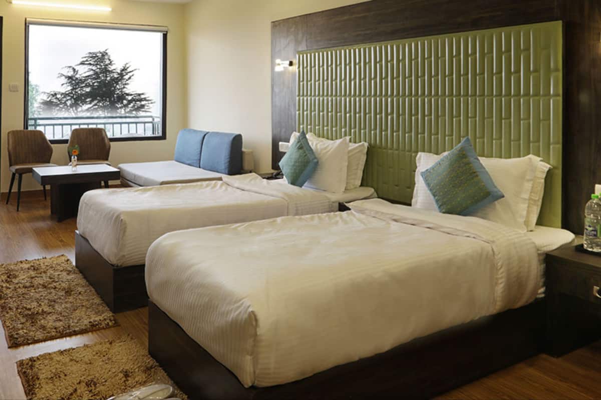 Een hotelkamer met twee bedden, een zithoek met een stoel en tafel, en een groot raam met uitzicht.