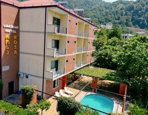 A hotel with multiple balconies, a swimming pool, and a view of a mountainous landscape. - Rosa Hotel Gonio (Batumi)