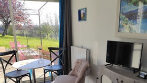 Una habitación de hotel con cama, escritorio con televisor, una silla y una mesa con sillas.