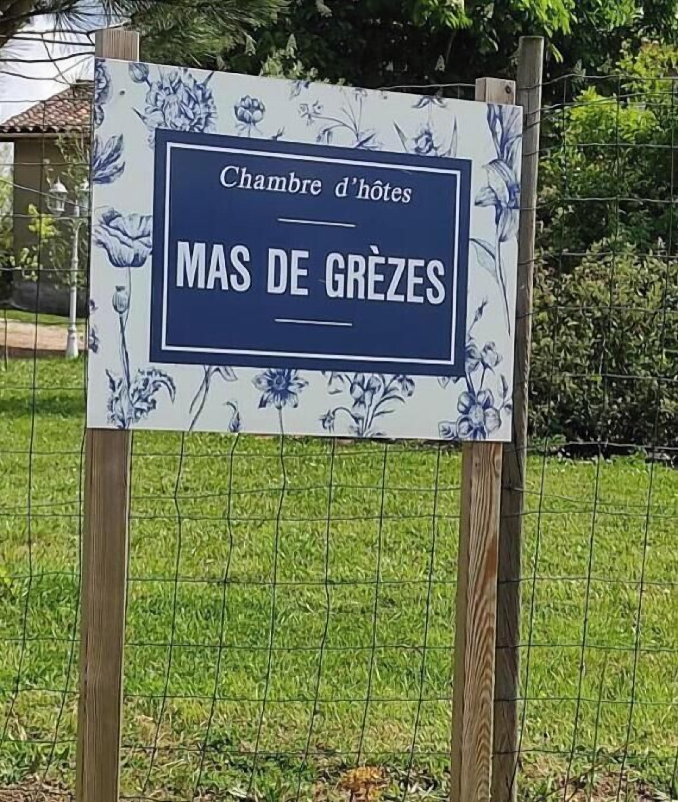 Señal para el hotel 'MAS DE GREZES', mostrando un plano de habitación con motivos florales.