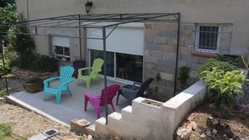 Une terrasse agrémentée de chaises Adirondack aux couleurs vives, d’un bac à fleurs en béton et d’un petit arbre.
