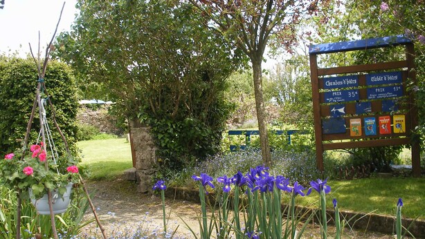 Un jardín con un letrero que muestra los precios de las habitaciones y una mesa.