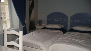 Un dormitorio con dos camas, una mesita de noche, una lámpara y una silla.