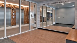Ein moderner Fitnessraum mit Glaswänden, Holzboden und motivierenden Sprüchen an der Wand.