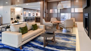 Eine moderne Hotelhalle mit einer Couch, Sesseln, einem Couchtisch und einem Kamin.