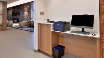 A modern office space with a desk, computer, and a trash bin.