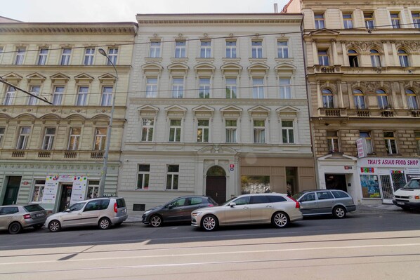 A multi-story building with a classical architectural style, featuring a central entrance with a large door and a small balcony above.