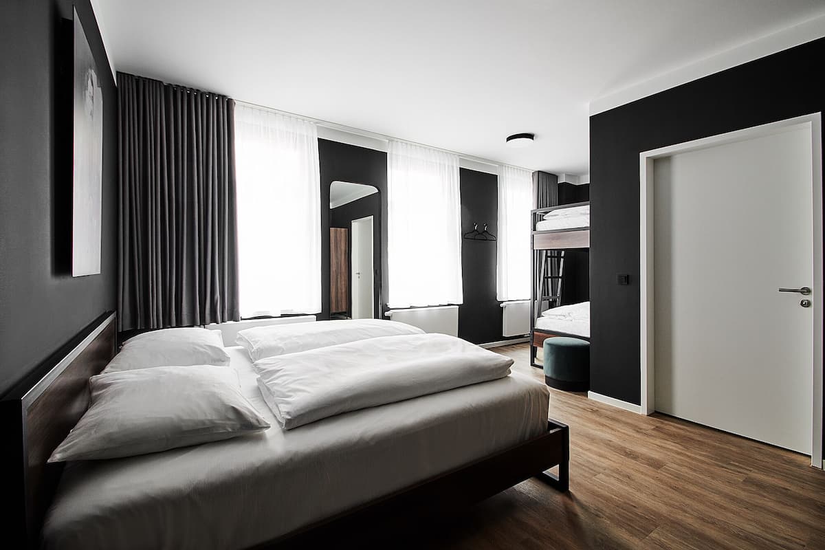 Ett modernt hotellrum med en stor säng, ett skrivbord och en våningssäng.
