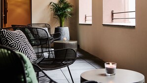 Un área de descanso moderna con un sofá, sillas, una mesita y una planta en maceta.