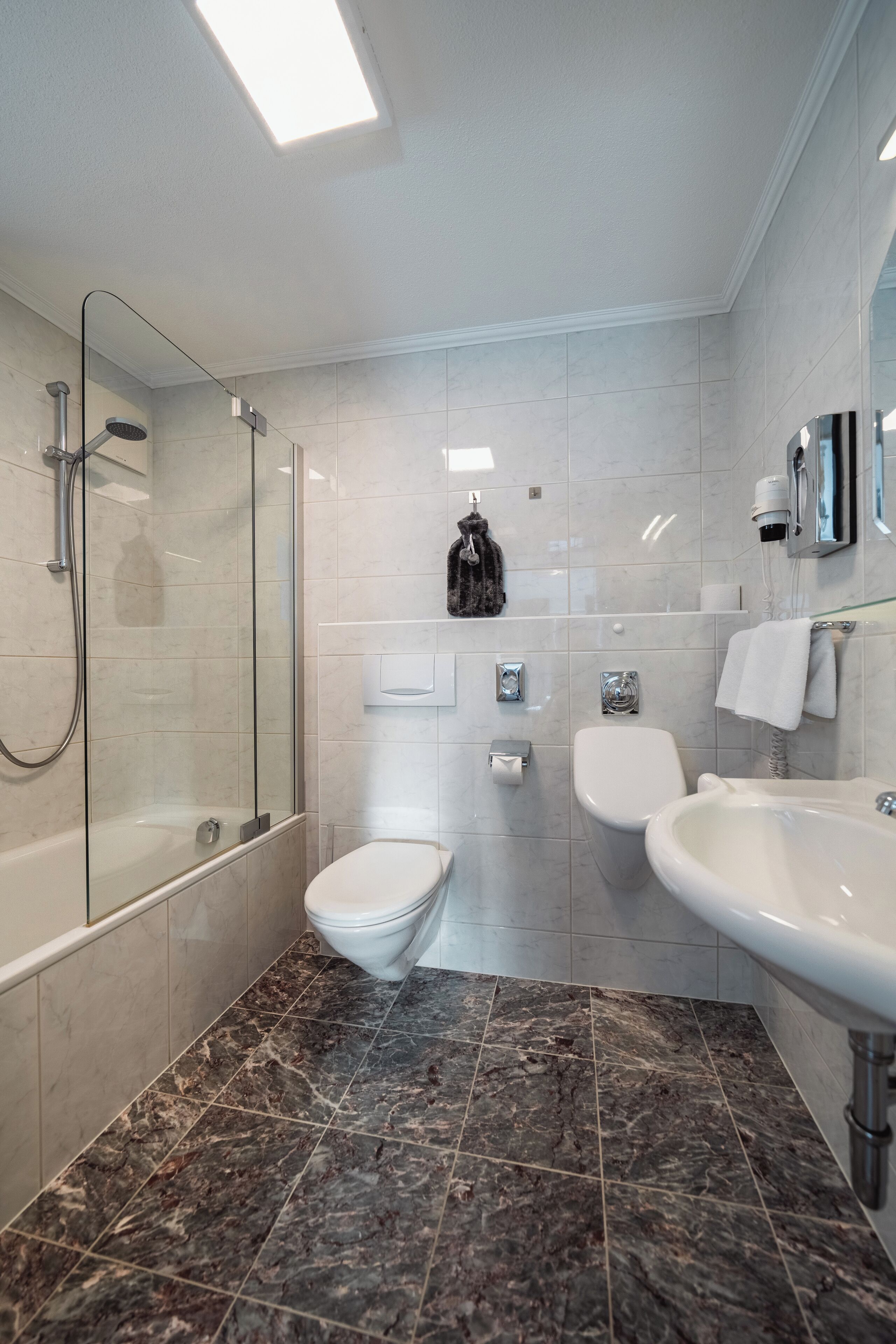 Un baño moderno con ducha de vidrio, inodoro y lavabo.