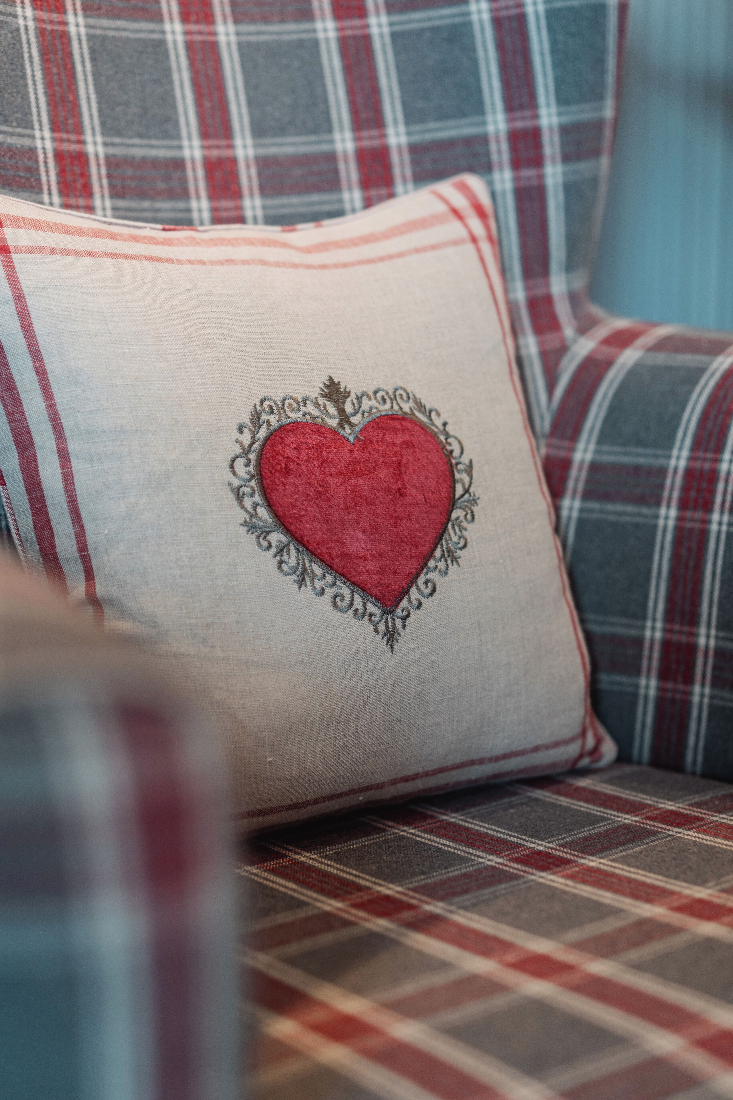 A plaid-patterned sofa with a cushion featuring a heart design.