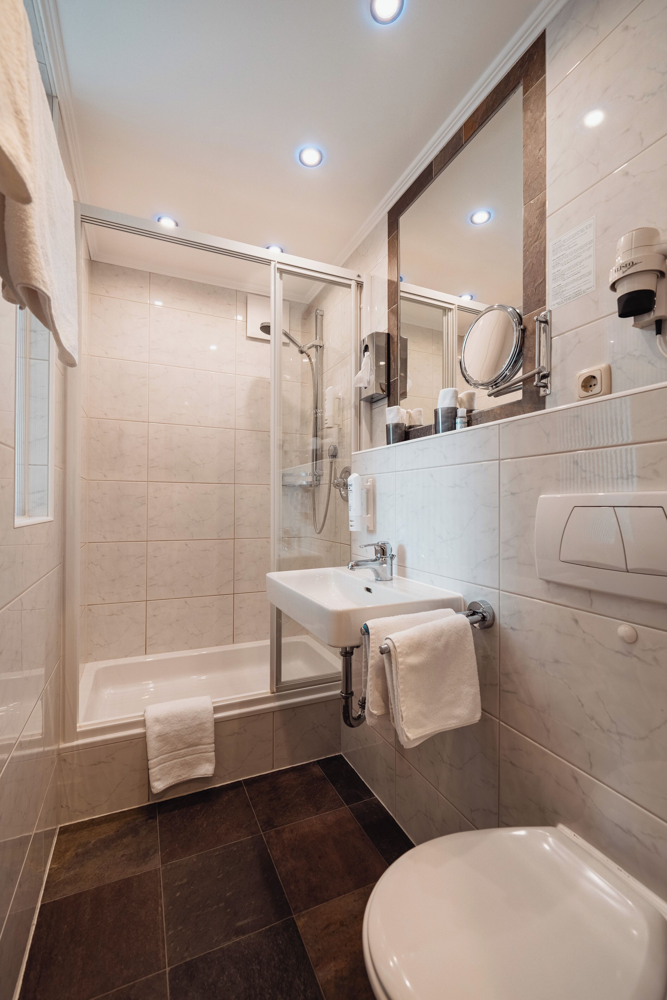 A modern bathroom with a bathtub, shower, and toilet.