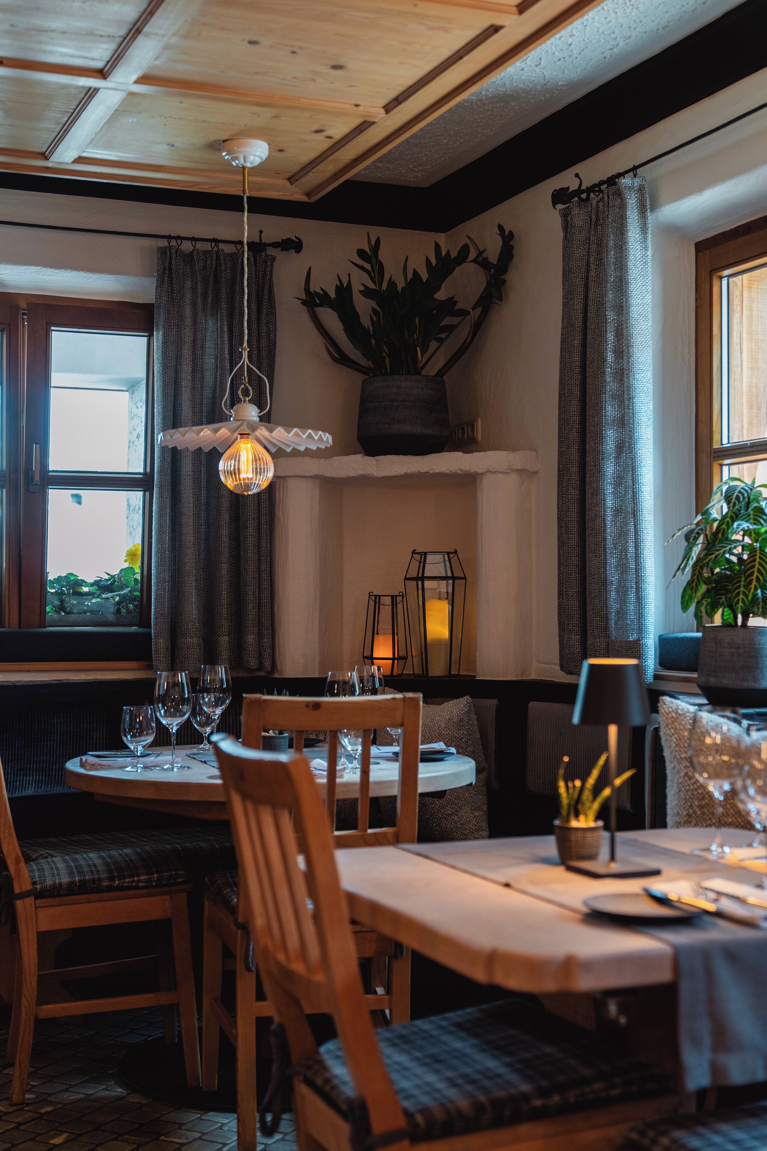 A cozy dining area with wooden furniture, a hanging light fixture, and a potted plant.