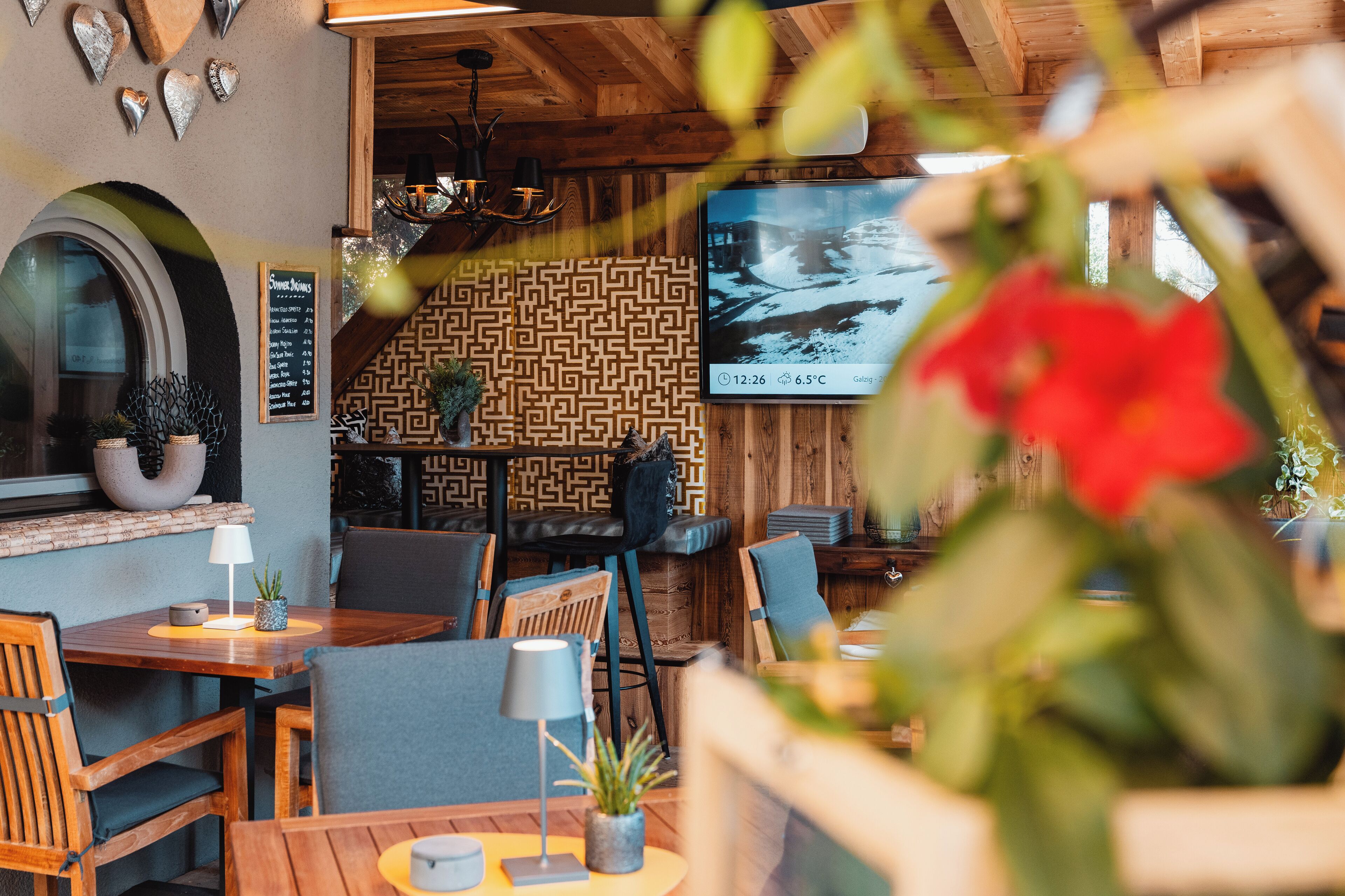 Interior acollidor d'un restaurant amb parets de fusta, una decoració mural amb motius i una pissarra amb el menú.