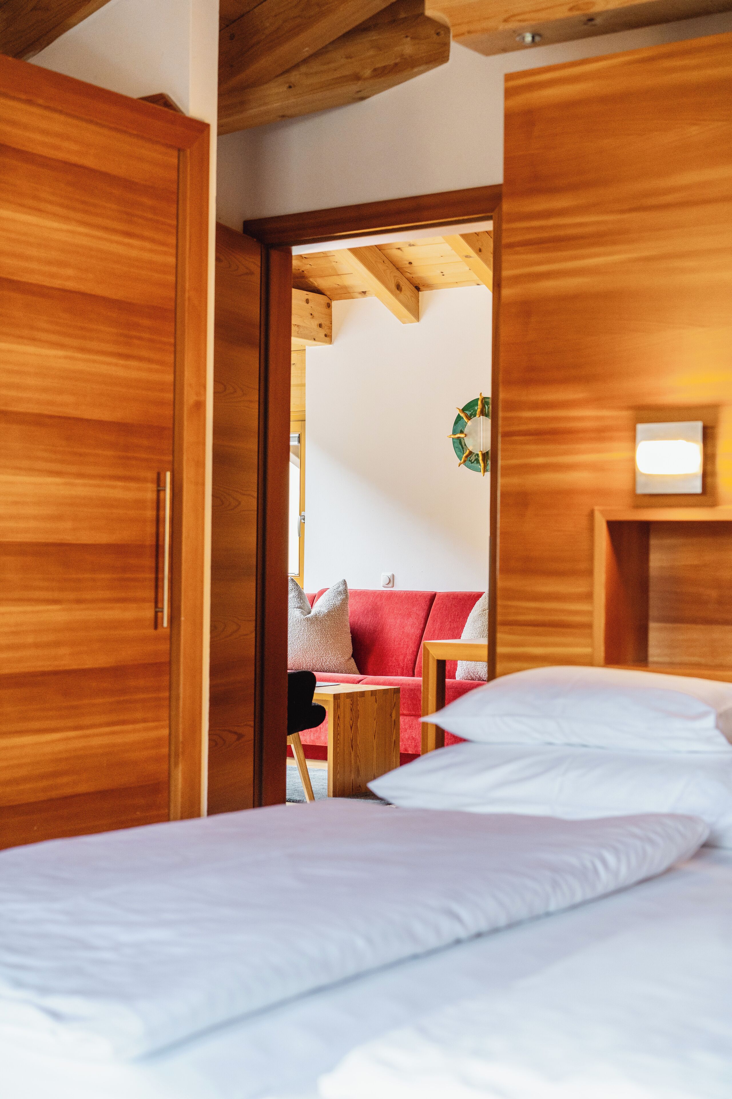 A bedroom with a wooden bed, a red sofa, and a small table.