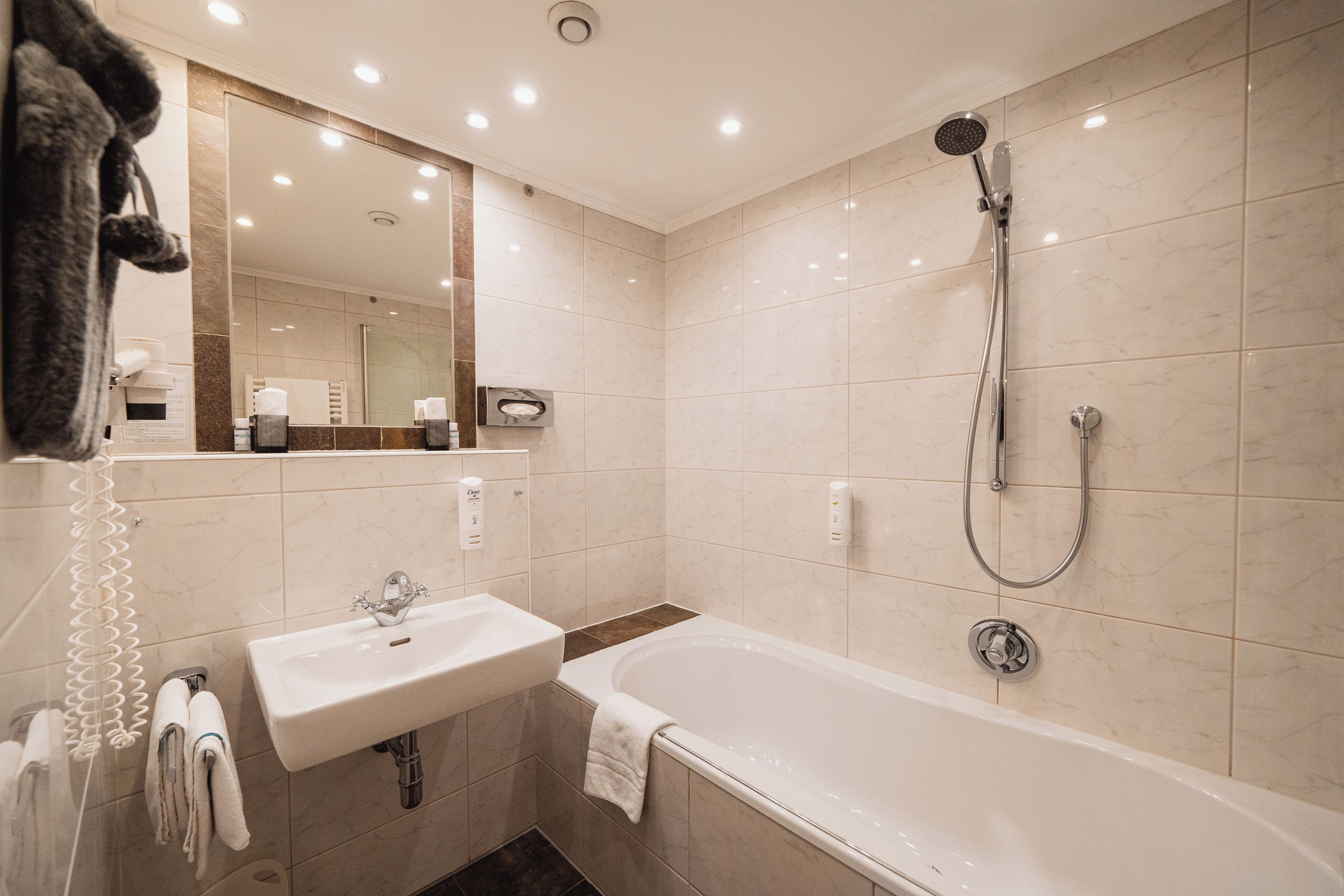 Un baño moderno con lavamanos, espejo y bañera.