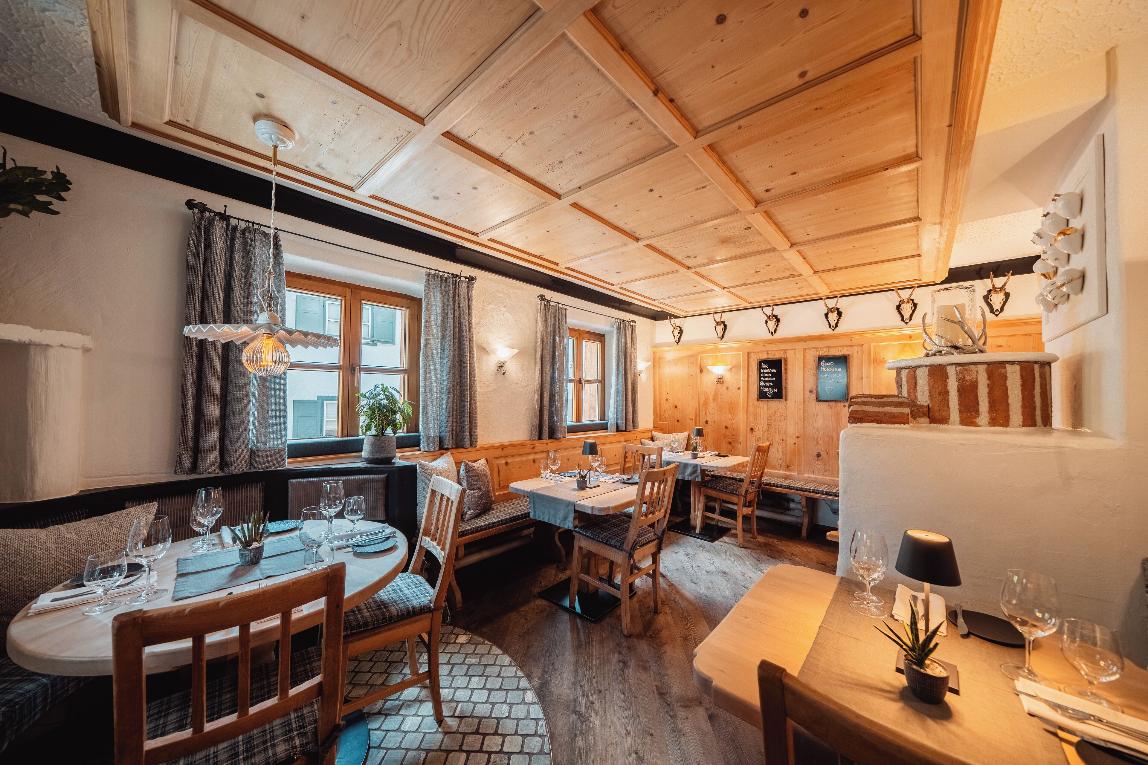 A cozy restaurant with wooden tables and benches, warm lighting, and a rustic interior.