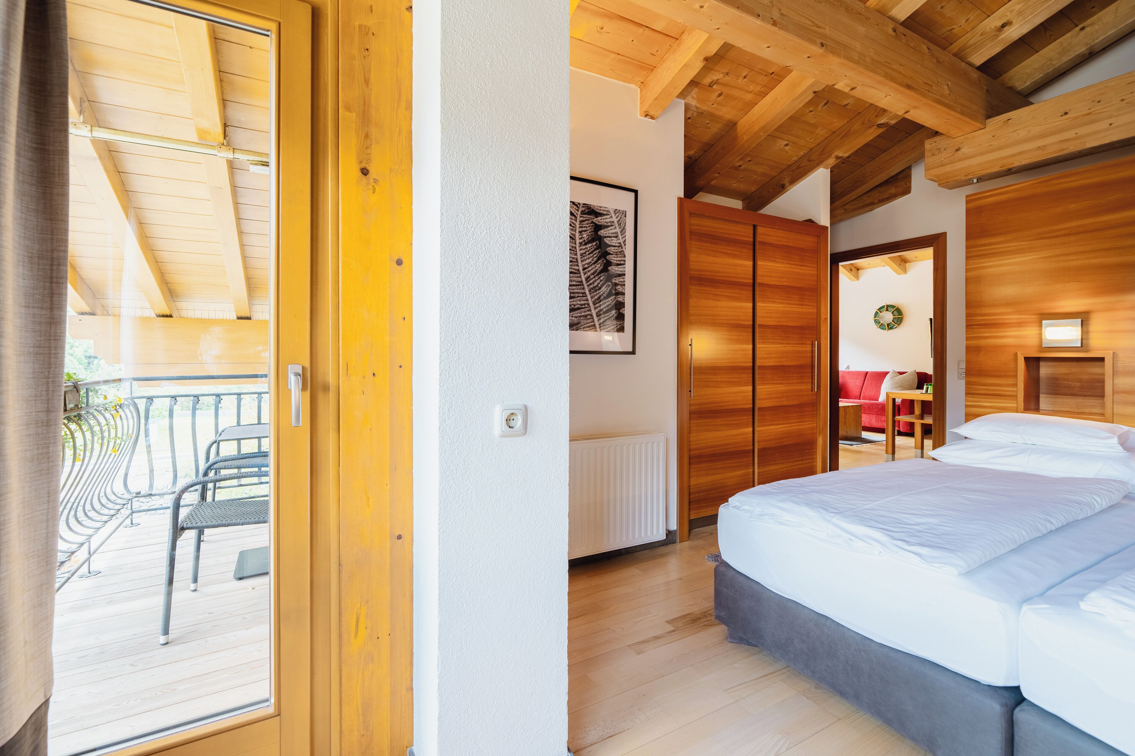 A bedroom with a wooden ceiling, a bed, a radiator, and a framed picture on the wall.