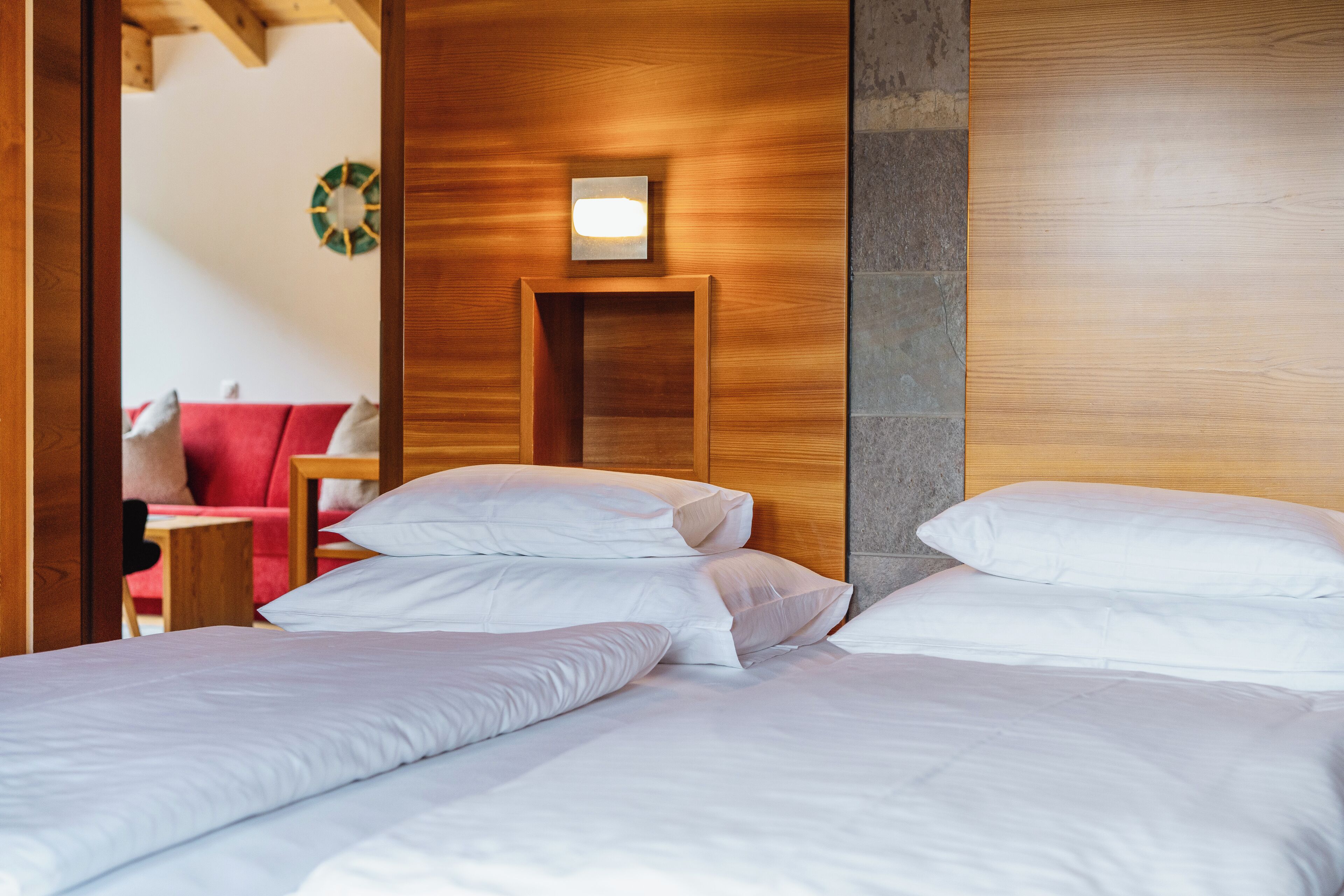 A hotel room with two beds, wooden headboards, a small bedside table, and a wall-mounted light fixture.
