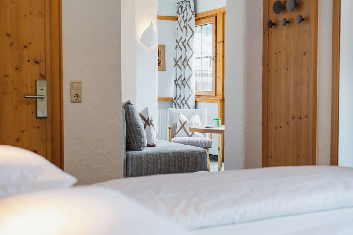 Une chambre à coucher avec un lit, une chaise et une table sur laquelle se trouve une bouteille.
