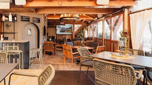 Um restaurante acolhedor com interiores em madeira, cadeiras de vime e um espaço de bar com garrafas de vinho.