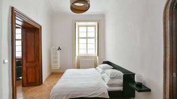 A bedroom with a bed, a bedside table, a window, and a radiator.