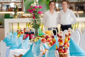 A dining table set with blue napkins, clear glasses, a pitcher of orange juice, and various snacks. - Villa i Restauracja Tymotka (Lublin)